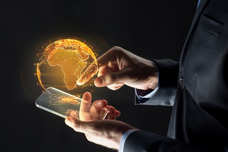 hands with smartphone and earth hologramの写真素材