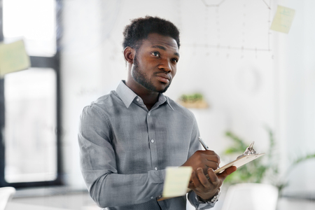 businessman with clipboard at office glass wall