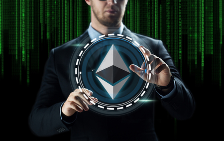 cryptocurrency, financial technology and business concept - businessman hand with ethereum hologram over binary code backgroundの写真素材