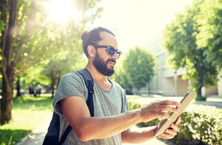 travel, tourism, backpacking, technology and people concept - man traveling with backpack and tablet pc computer in city searching locationの写真素材