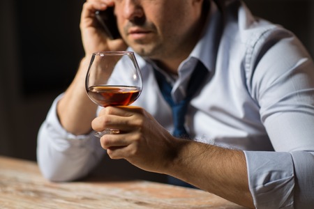 alcoholism, alcohol addiction and people concept - close up of male alcoholic drinking brandy and...