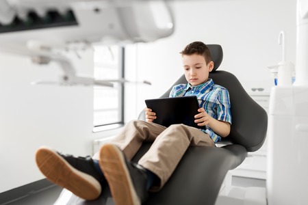 happy kid patient with tablet pc at dental clinicの写真素材