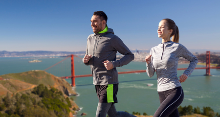 happy couple running over golden gate bridgeの写真素材