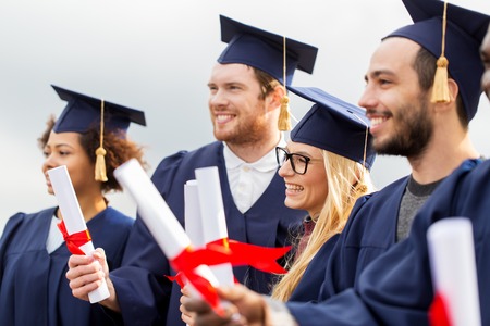 happy students in mortar boards with diplomas
