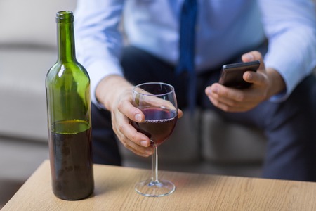 close up of man with alcohol and smartphoneの写真素材