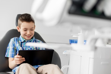 happy kid patient with tablet pc at dental clinic
