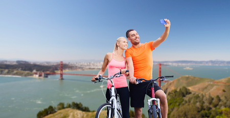 couple with bicycles taking selfie by smartphoneの写真素材