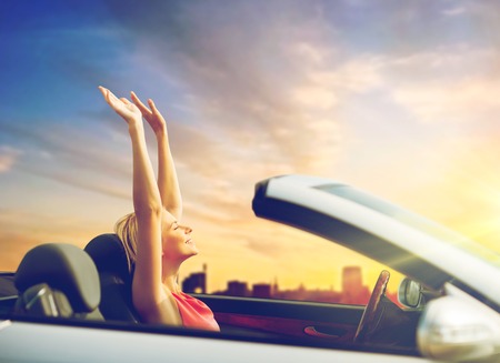 woman enjoying sunset in convertible car over cityの写真素材