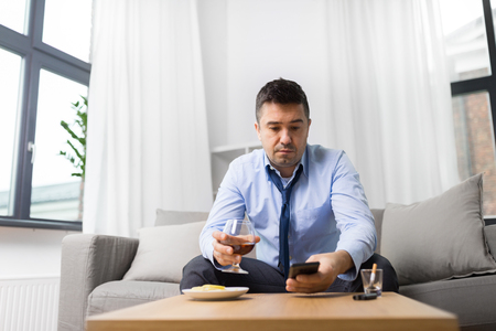 drunk man with smartphone and alcohol at homeの写真素材