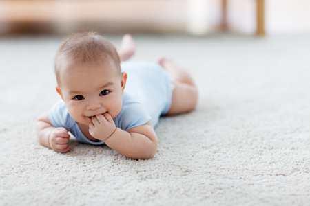 sweet little asian baby boy lying on floorの写真素材