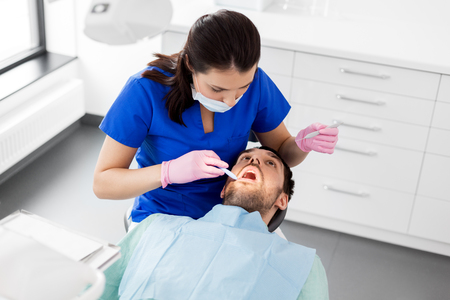 female dentist checking up male patient teethの写真素材