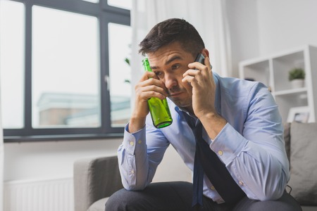 man with bottle of alcohol calling on smartphone