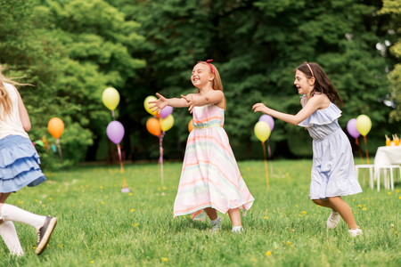 happy girls playing tag game at birthday partyの写真素材