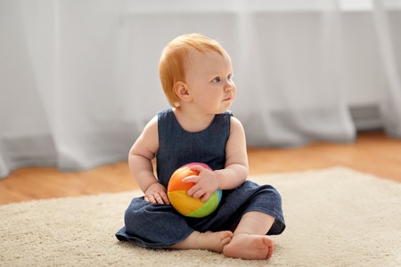 lovely redhead baby girl with toy ball at homeの写真素材