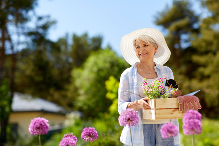 senior woman garden tools and flowers at summer