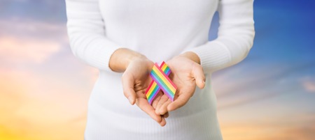 female hands holding gay pride awareness ribbonの写真素材