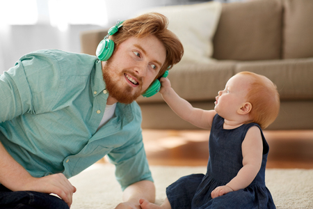 father in headphones with baby daughter at homeの写真素材