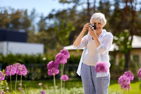 senior woman with camera photographing flowersの写真素材