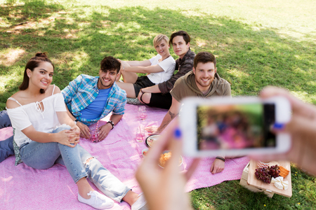 friends photographing by smartphone at picnicの写真素材