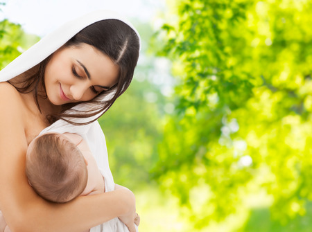 mother breast feeding baby over natural backgroundの写真素材