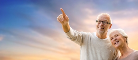 happy senior couple holding hands over evening skyの写真素材