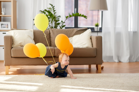 lovely redhead baby girl with balloons at homeの写真素材