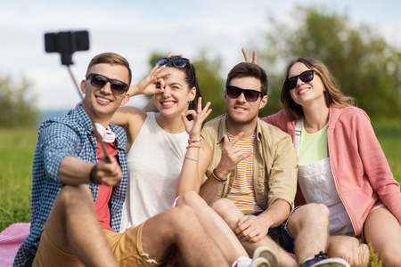 friends taking picture by selfie stick in summerの写真素材