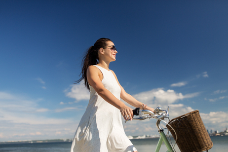 happy young woman with fixie bicycle at seasideの写真素材