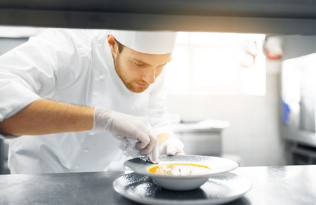 food cooking, profession and people concept - happy male chef cook serving plate of soup at restaurant kitchenの写真素材