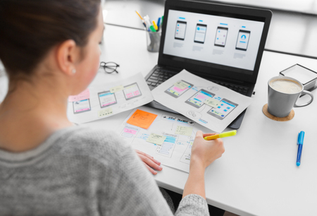 app design, technology and business concept - web designer or developer with sketches and laptop computer working on user interface at officeの写真素材