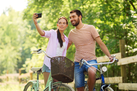 couple with bicycles taking selfie by smartphoneの写真素材