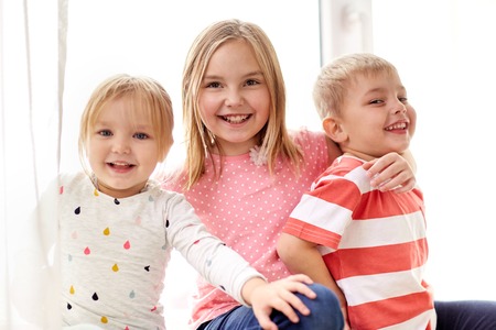 happy little kids hugging at windowの写真素材