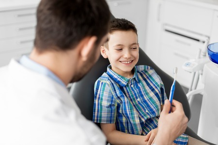 dentist giving toothbrush to kid patient at clinicの写真素材