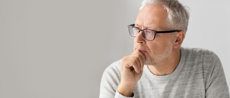 close up of senior man in glasses thinking