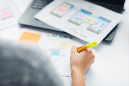 app design, technology and business concept - web designer or developer with sketches and laptop...