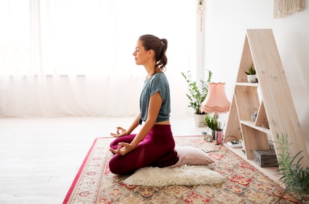 woman meditating in lotus pose at yoga studio