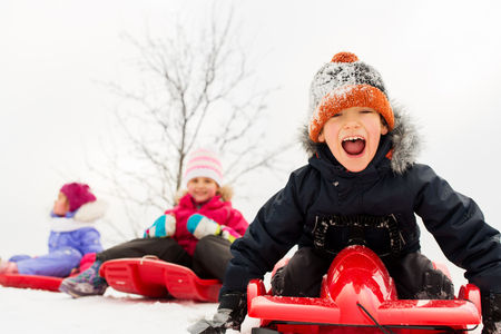 happy kids sliding on sleds in winterの写真素材