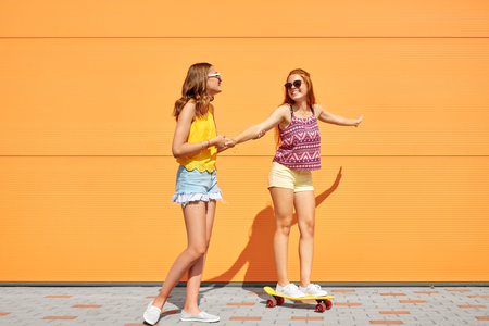 teenage girls riding skateboard on city streetの写真素材