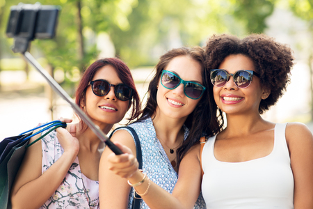 women with shopping bags taking selfie outdoorsの写真素材