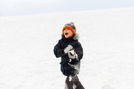 happy little boy playing with snow in winterの写真素材
