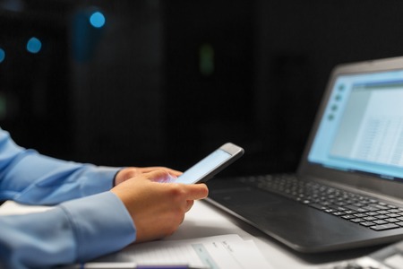 close up of hands with smartphone at night officeの写真素材