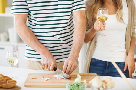 couple cooking food and drinking wine at homeの写真素材