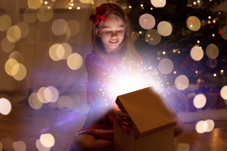 smiling girl opening christmas gift at nightの写真素材