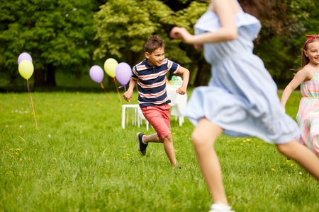 happy kids playing tag game at birthday partyの写真素材
