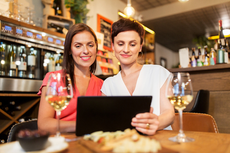 women with tablet pc at wine bar or restaurantの写真素材