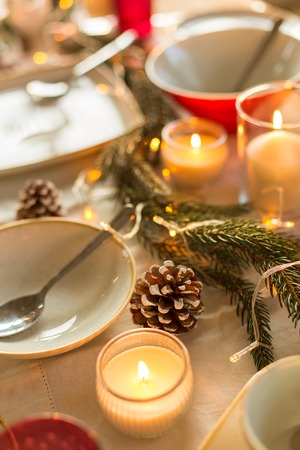 christmas, holidays and decoration concept - table served and decorated for festive dinner with candles, pine cones and fir branchの写真素材