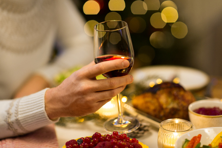 holidays and celebration concept - close up of man having christmas dinner and drinking red wineの写真素材