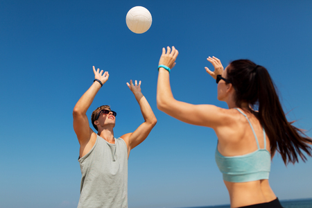 happy couple playing volleyball on summer beachの写真素材