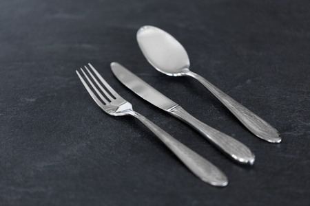 table setting, cutlery and eating concept - close up of fork, knife and spoon