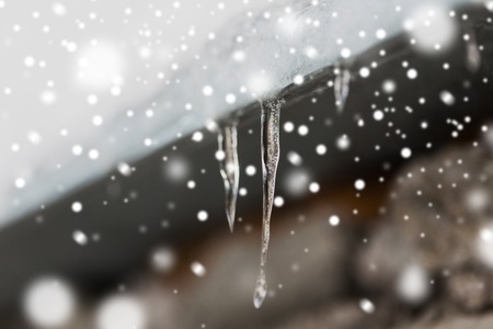 icicles and snow hanging from building roofの写真素材